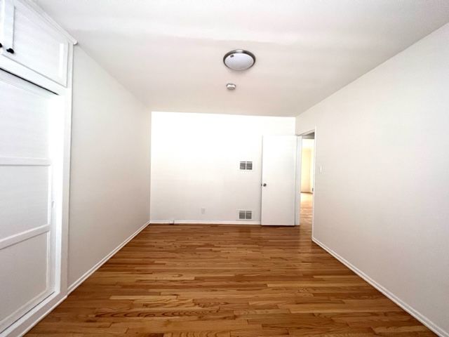 An empty room with hardwood floors and white walls