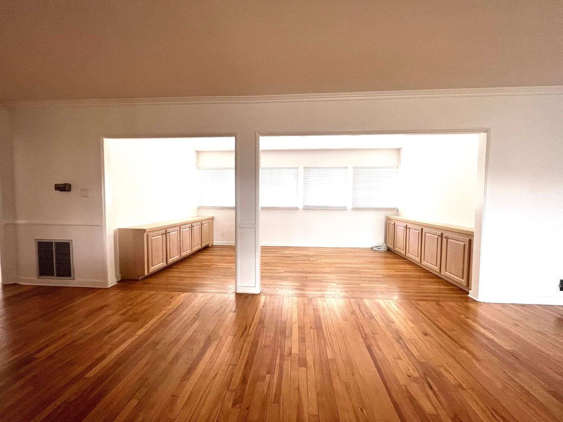 An empty room with hardwood floors and white walls