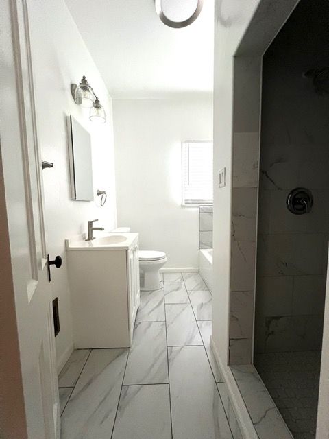 A bathroom with a toilet , sink , mirror and shower.