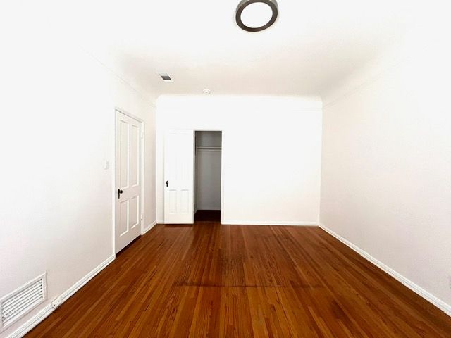 An empty room with hardwood floors and white walls.