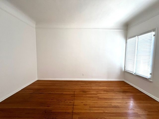 An empty room with hardwood floors and white walls.