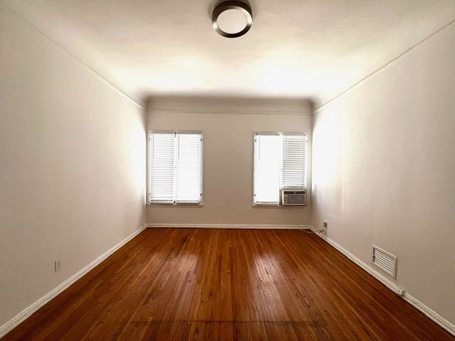An empty room with hardwood floors and white walls.