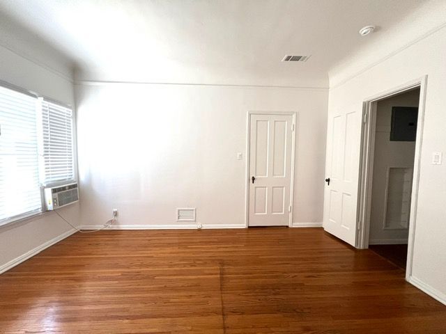 An empty living room with hardwood floors and white walls.