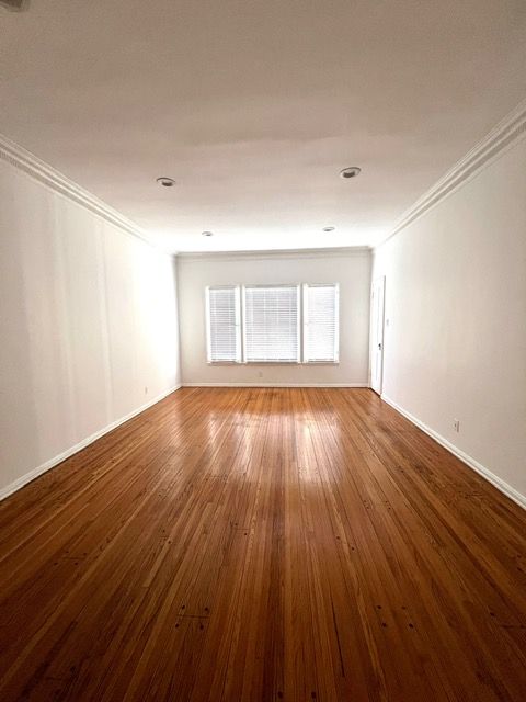 An empty living room with hardwood floors and white walls.