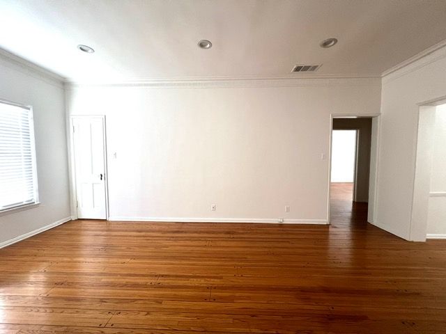 An empty living room with hardwood floors and white walls.