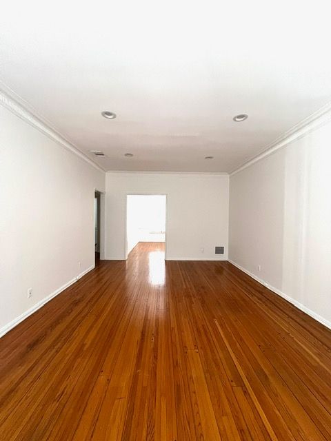 An empty room with hardwood floors and white walls.