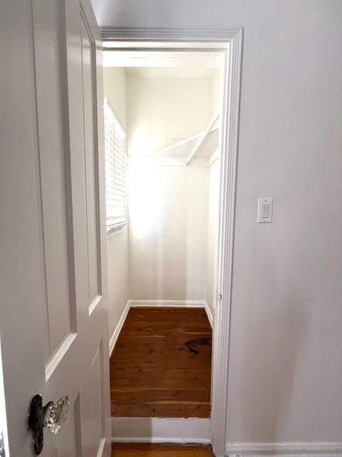 A walk in closet with wooden floors and white walls.