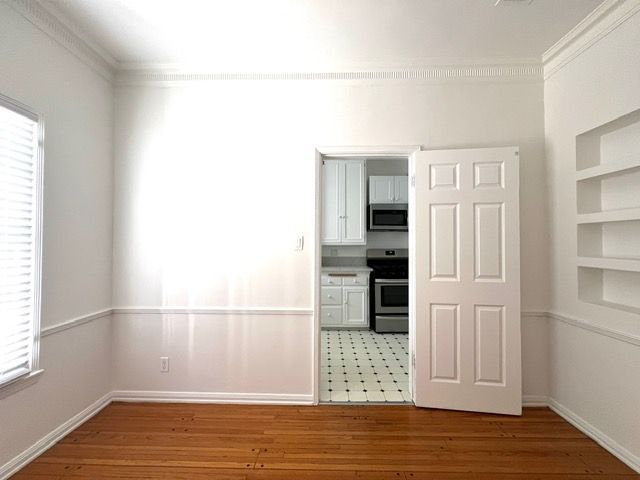 An empty room with a door open to a kitchen