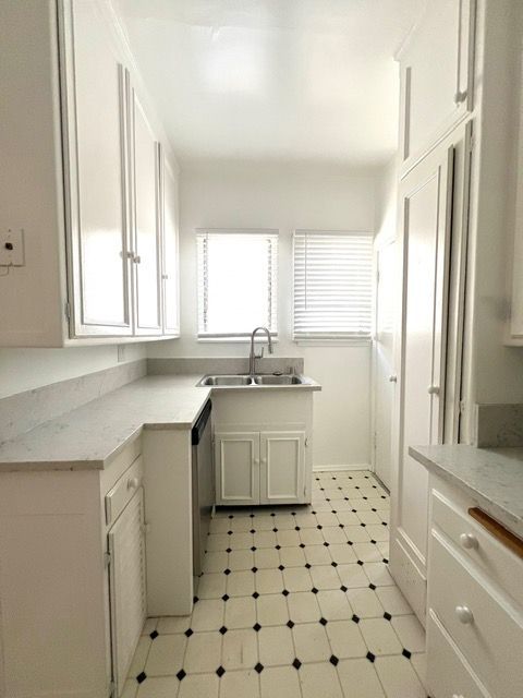 A kitchen with white cabinets and a black and white tile floor.