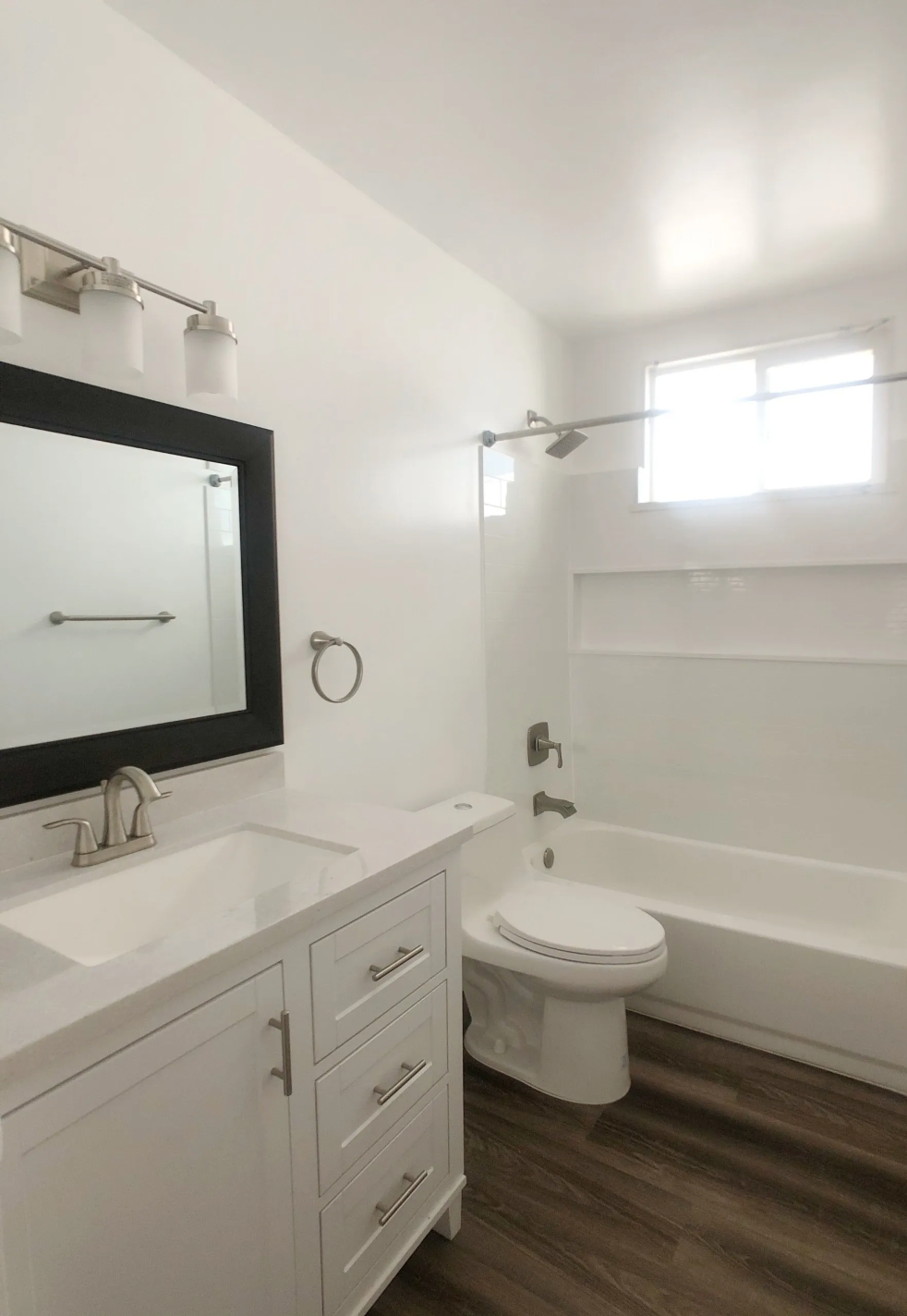 A bathroom with a sink , toilet , tub and mirror.
