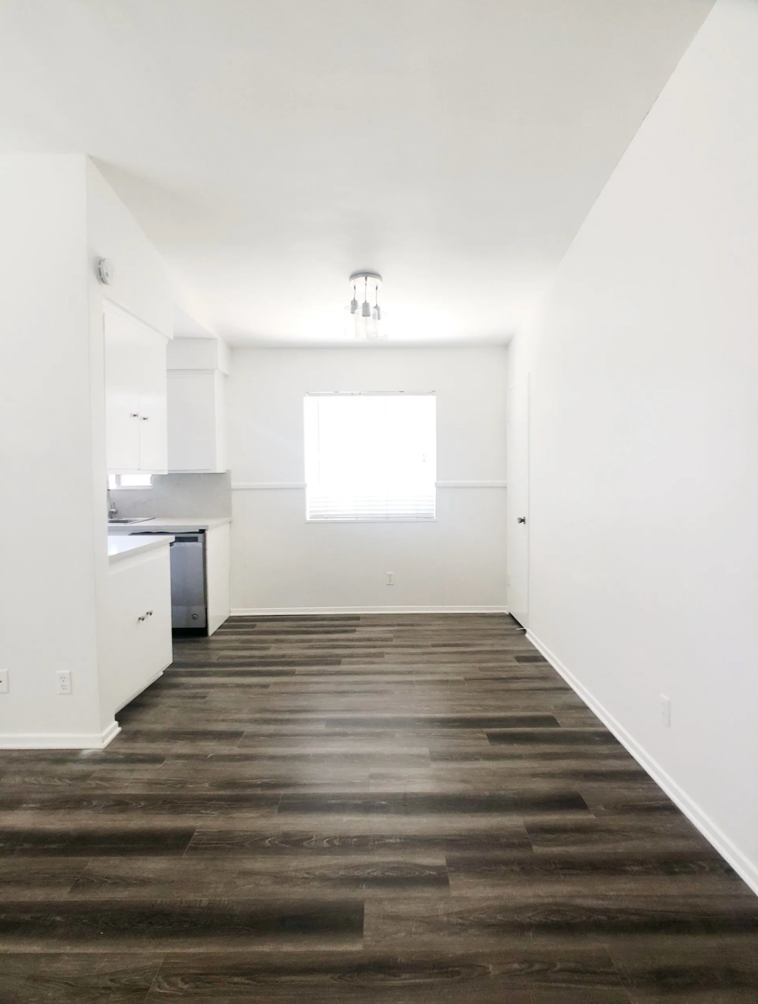 An empty room with hardwood floors and white walls