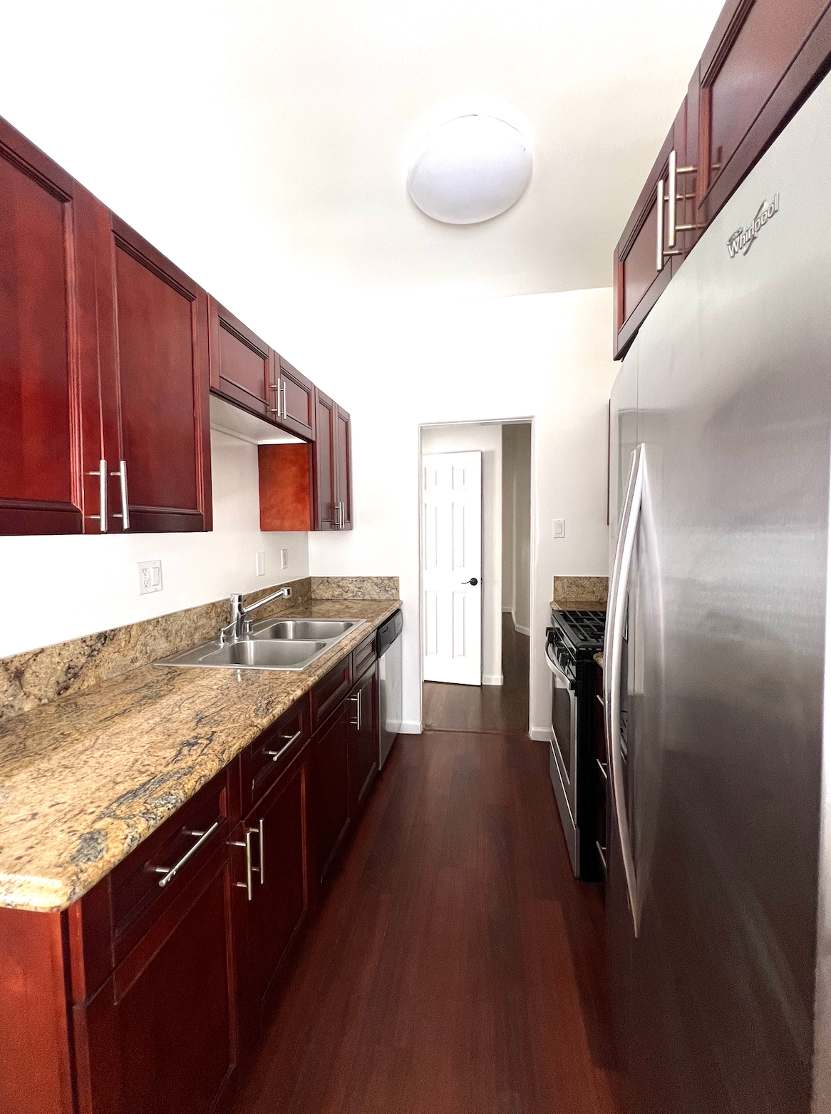 A long kitchen with stainless steel appliances and wooden cabinets