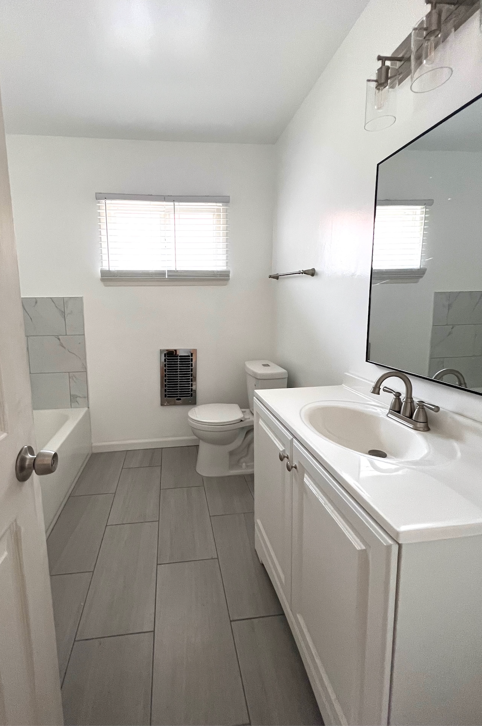 A bathroom with a toilet , sink , and mirror.