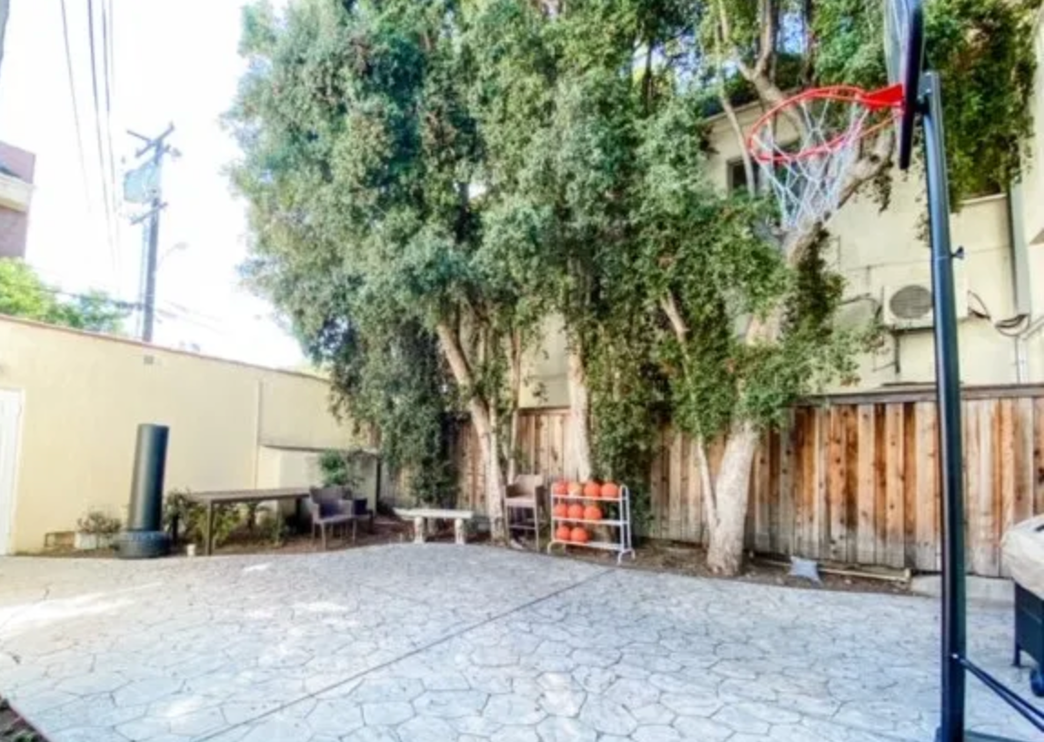 There is a basketball hoop in the backyard of a house.