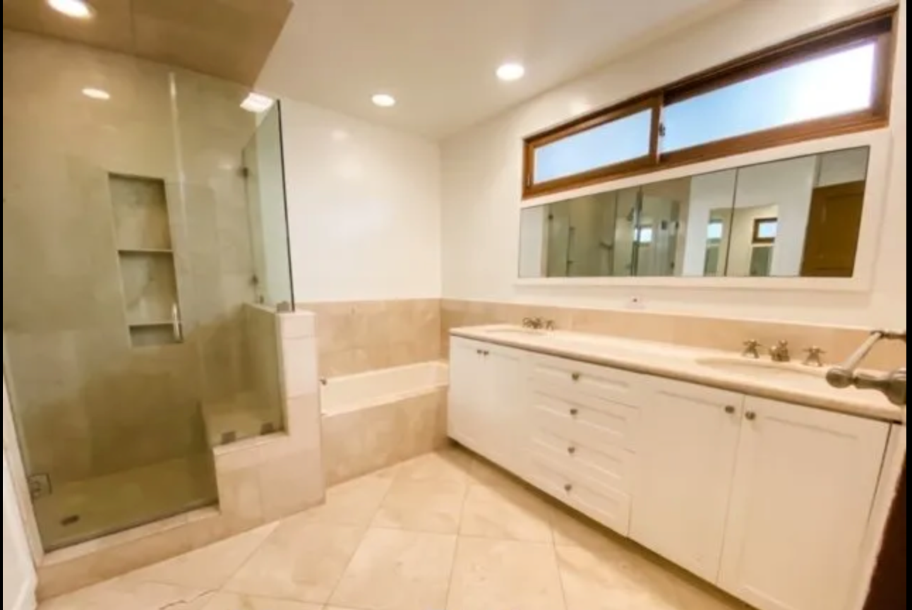 A bathroom with two sinks and a walk in shower
