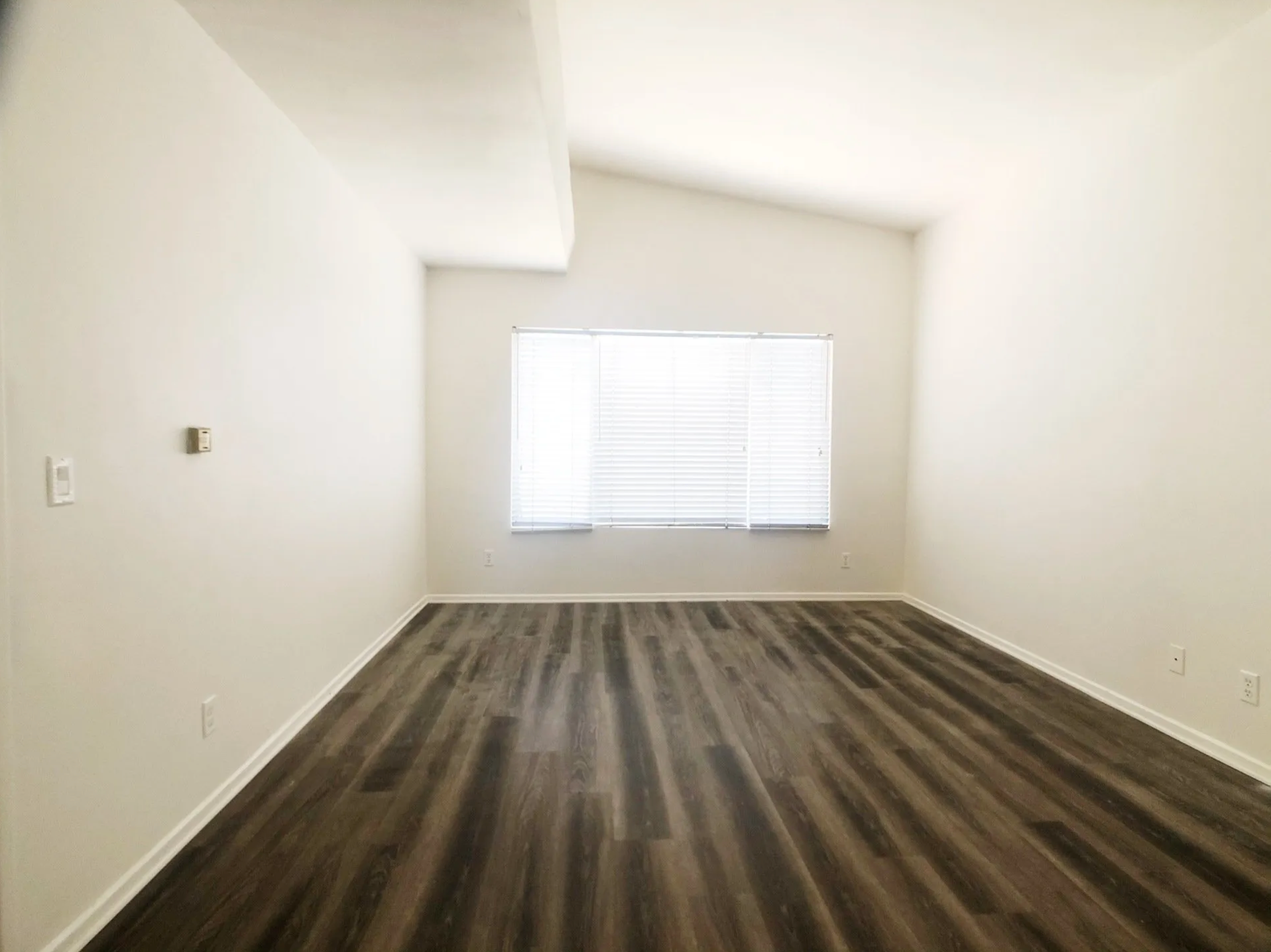 An empty room with hardwood floors and a window.