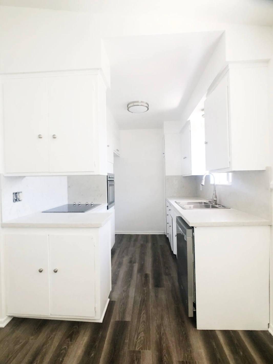A kitchen with white cabinets and hardwood floors