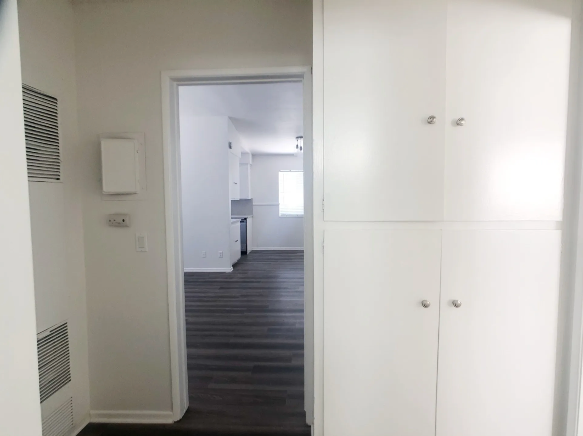 A hallway in a house with a doorway leading to a kitchen.