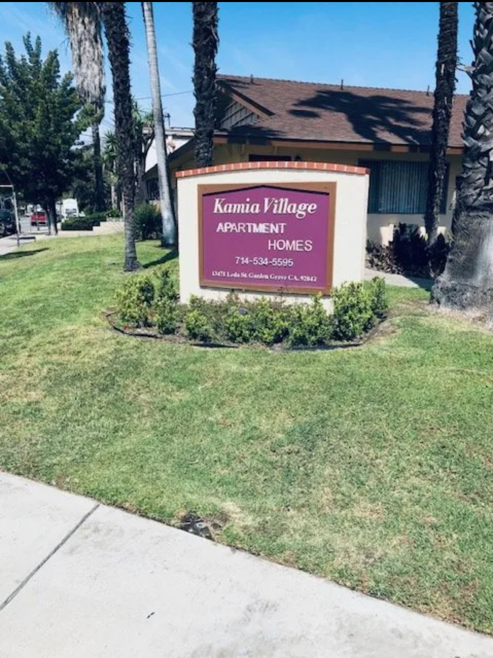 A sign for kasso village apartment homes sits in front of a house