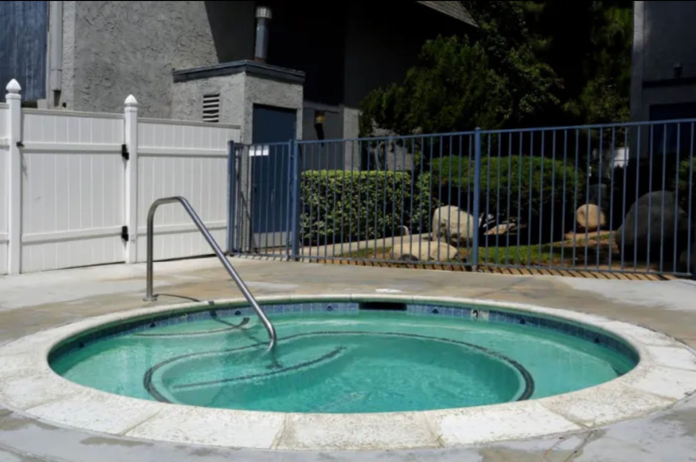 A hot tub is surrounded by a fence and a white fence