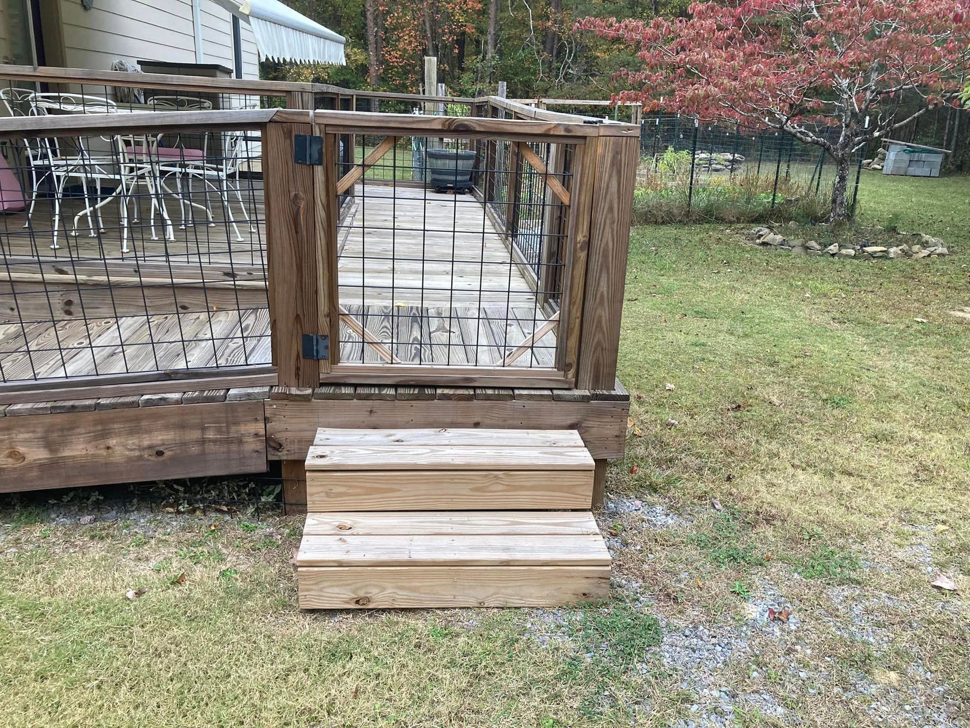 A wooden deck with a gate and stairs leading to it.
