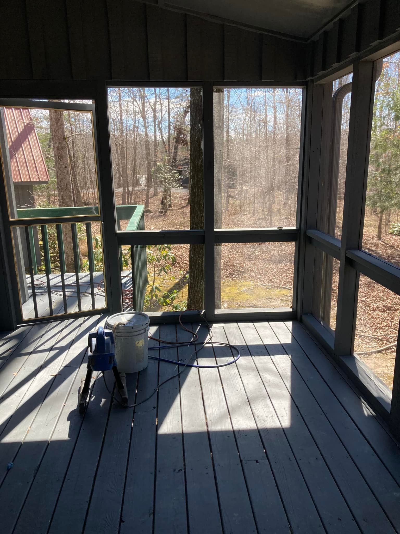 A screened in porch with a view of the woods.