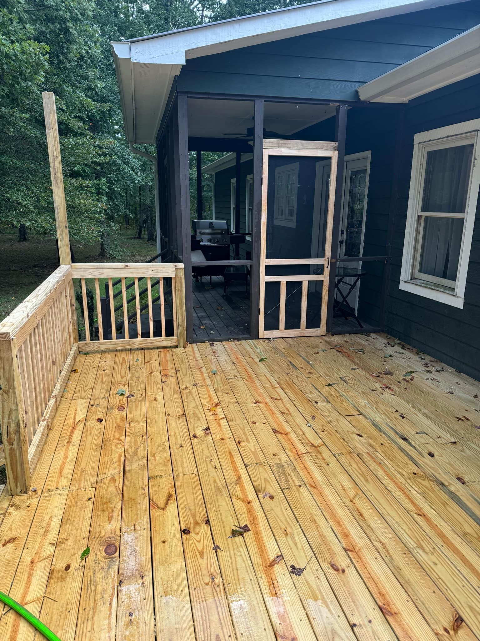 A screened in porch with a wooden deck in front of a house.