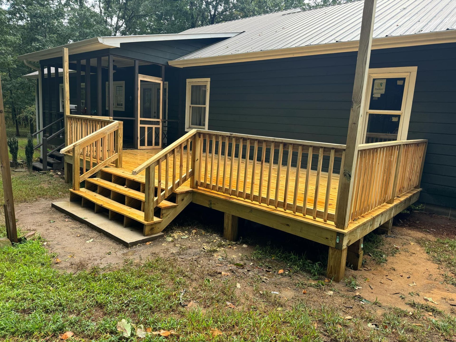 A black house with a wooden deck and stairs in front of it.