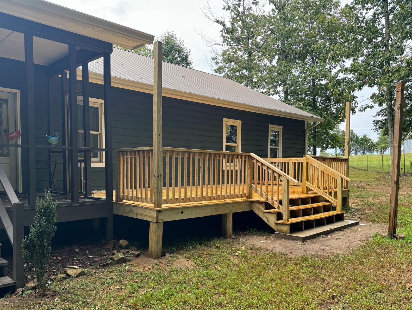A small black house with a wooden deck and stairs.