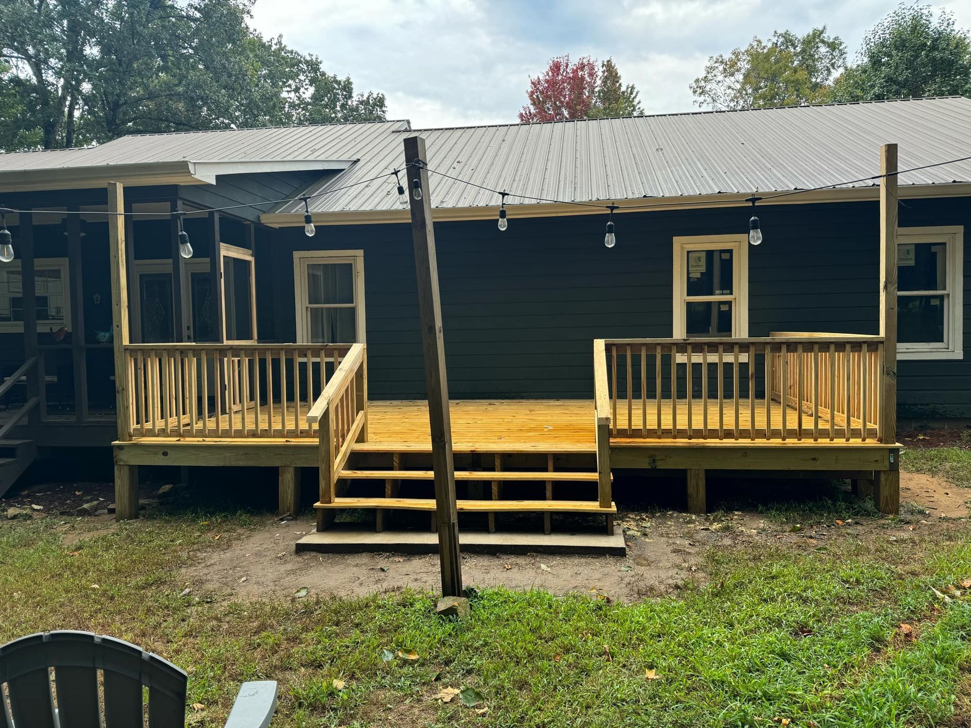 A black house with a wooden deck in front of it