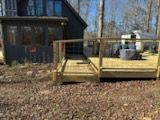 A wooden deck is sitting in front of a house in the woods.