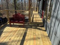 There is a wooden deck with a red bench on it.