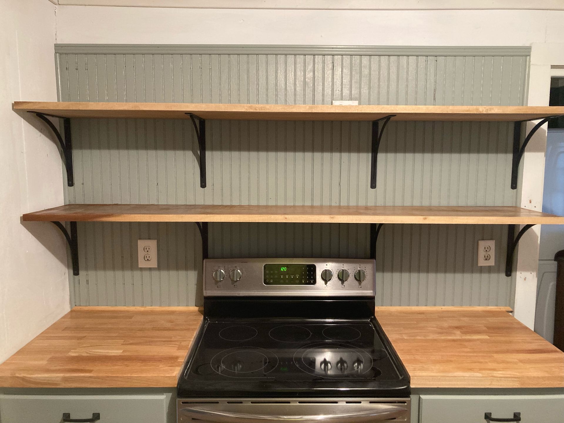 A kitchen with a stove and shelves above it