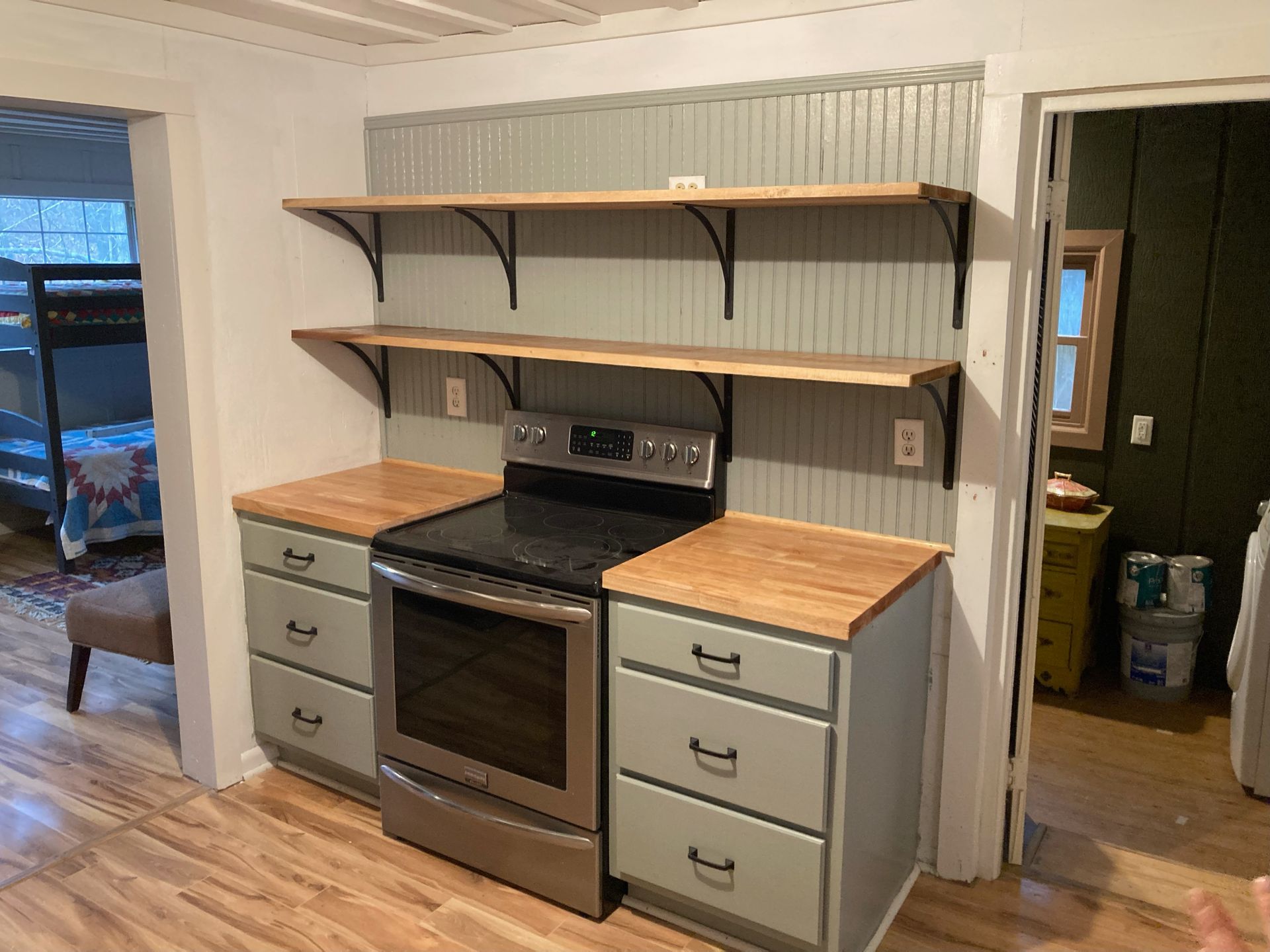 A kitchen with a stove , oven , drawers and shelves.
