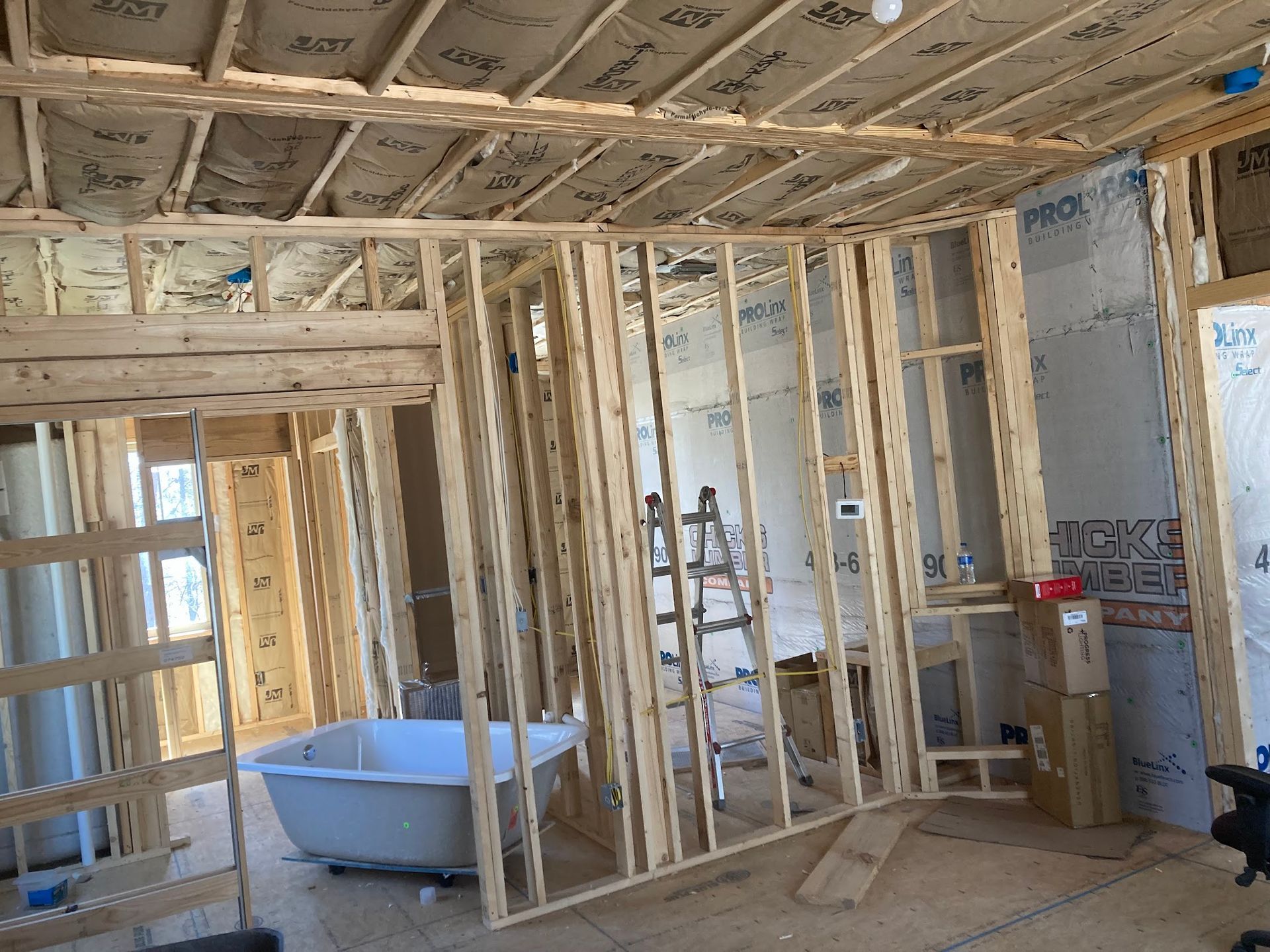 A bathtub is sitting in the middle of a room under construction.