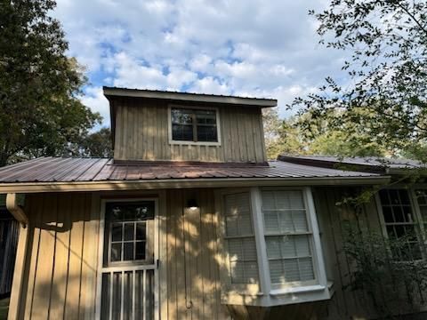 A small house with a metal roof and a bay window.