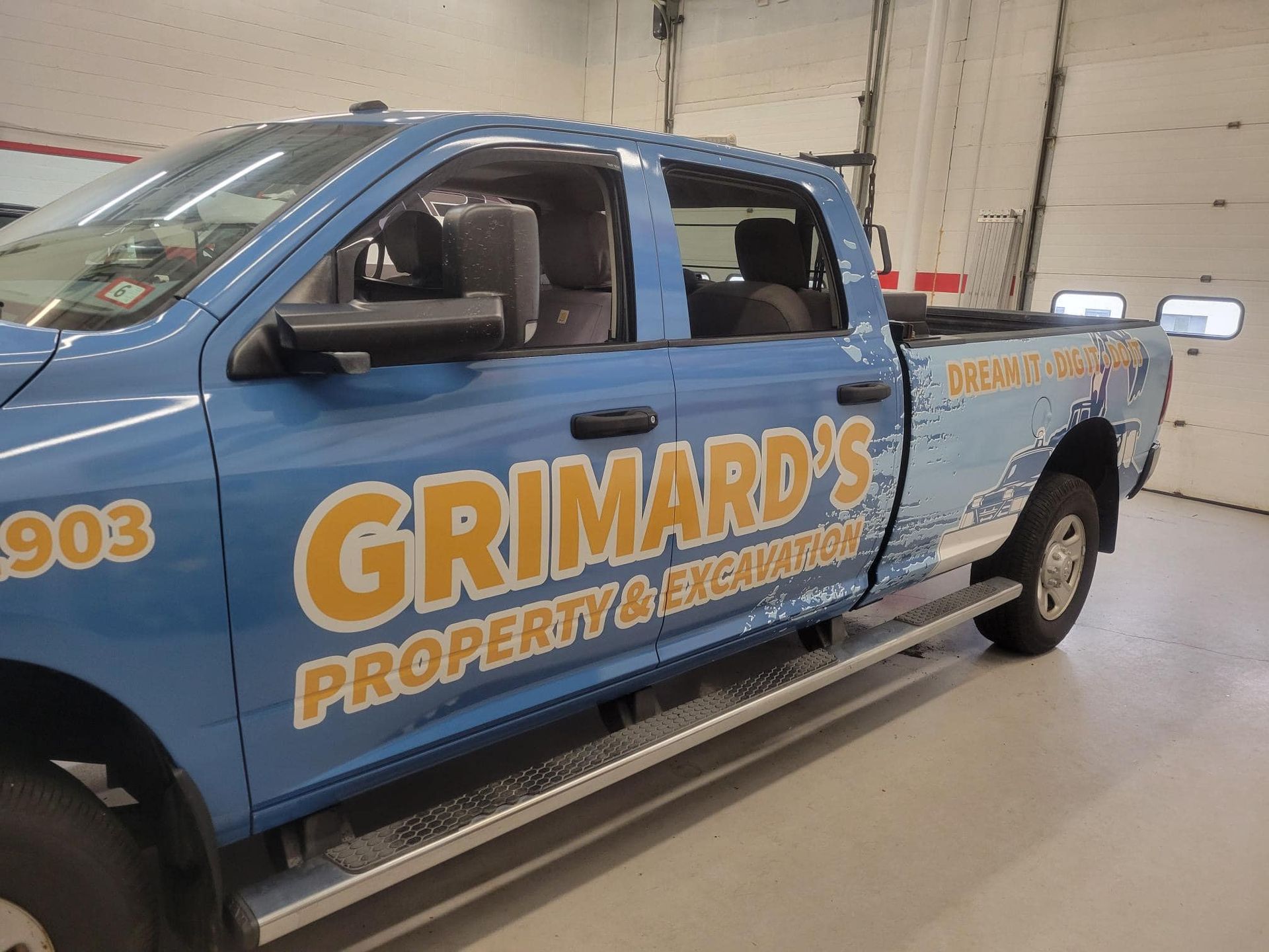 Blue Grimaldi's property & snow removal truck parked indoors with company logo and phone number on the side