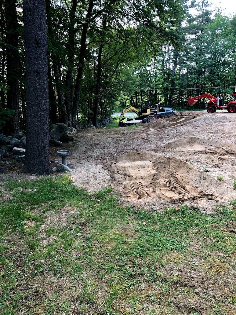 Mud-covered path through a wooded area with parked cars and a red vehicle in the distance