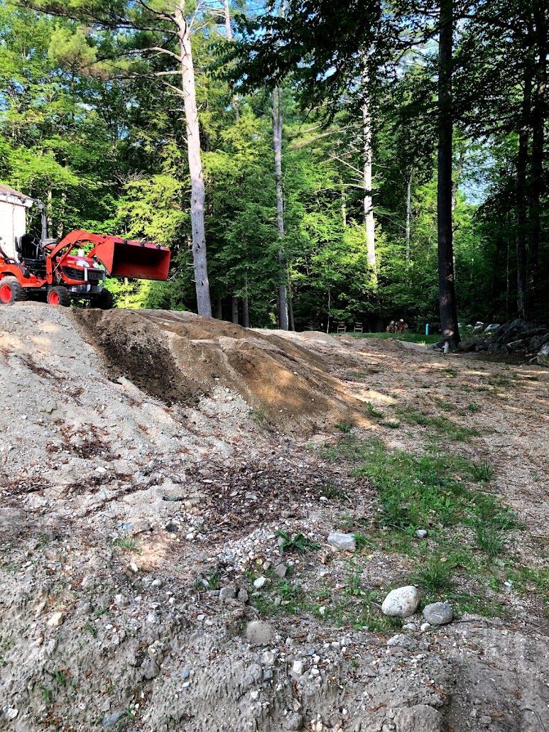 Red dump truck on a rocky dirt slope in a forest clearing