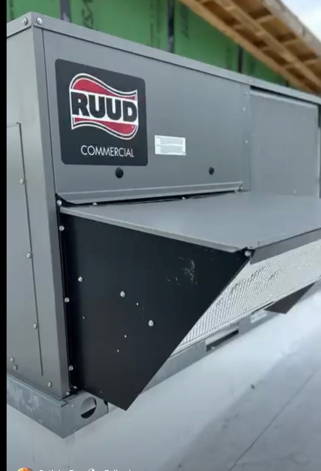 RUUD rooftop commercial HVAC unit with black and gray panels on a roof.