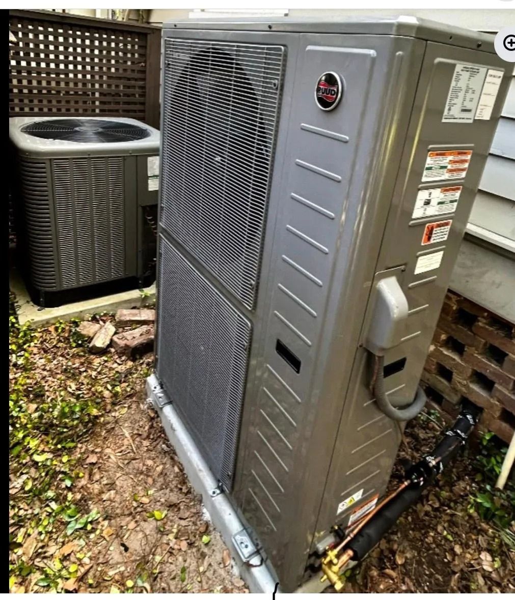 Outdoor HVAC unit beside a house, with a large gray condenser and another unit in the background.