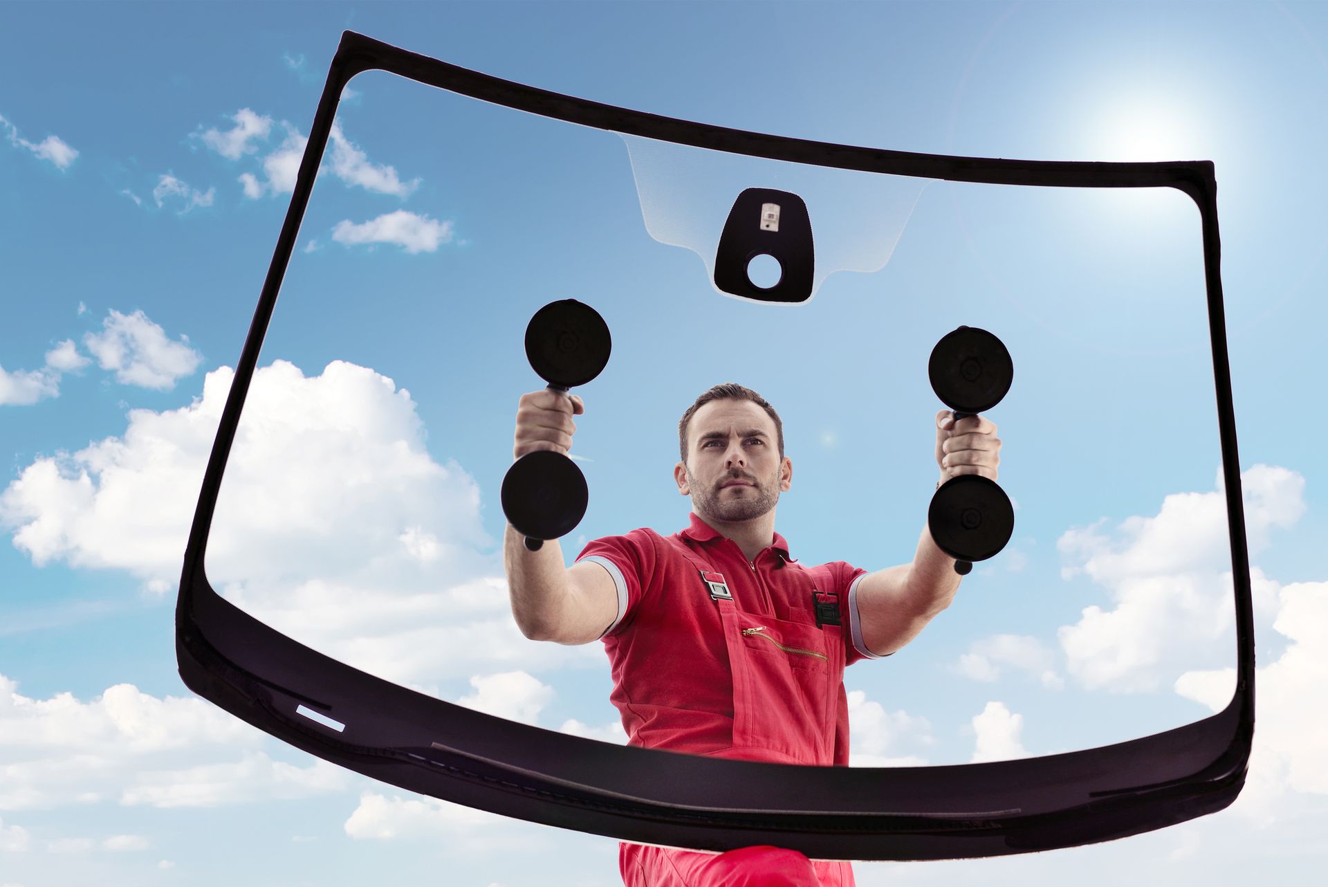 A man lifting a car windshield, illustrating the procedure involved in auto glass replacement.