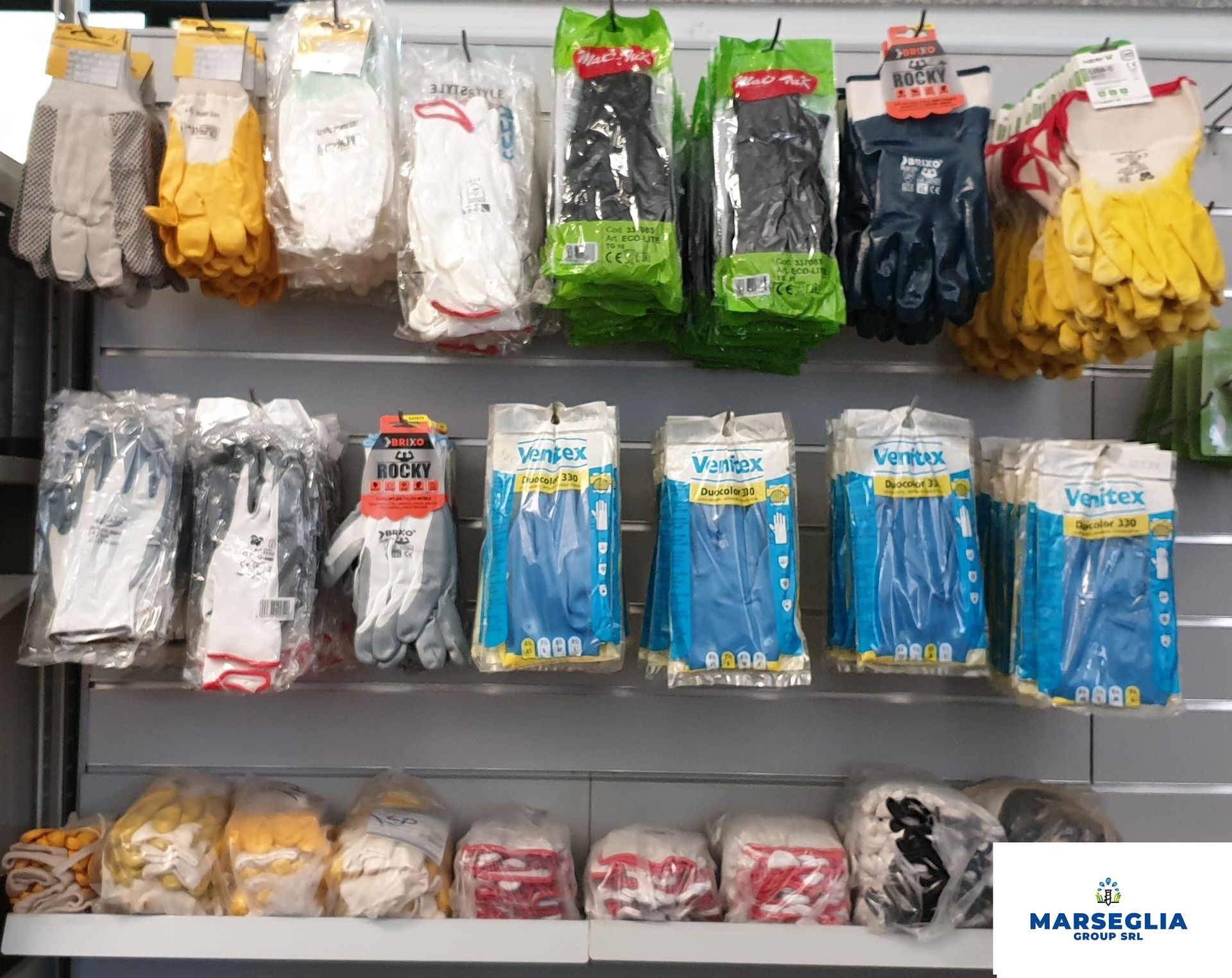 Guanti di vari colori e stili sono esposti sugli scaffali di un negozio.