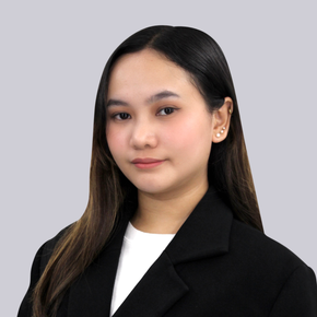 Studio portrait of a person with long dark hair in a black blazer against a gray background