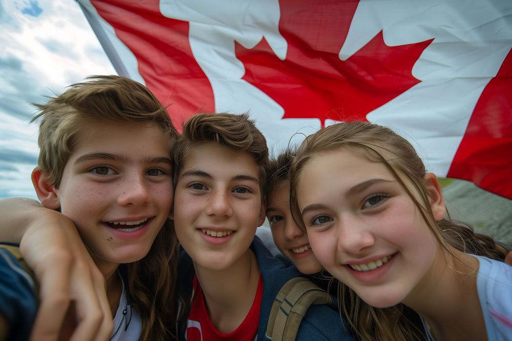 Three smiling friends posing in front of a waving Canadian flag