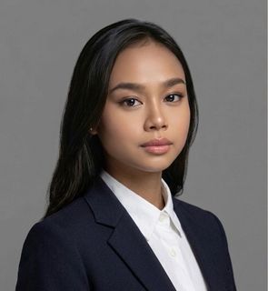 Portrait of a person in a navy blazer and white shirt against a gray background