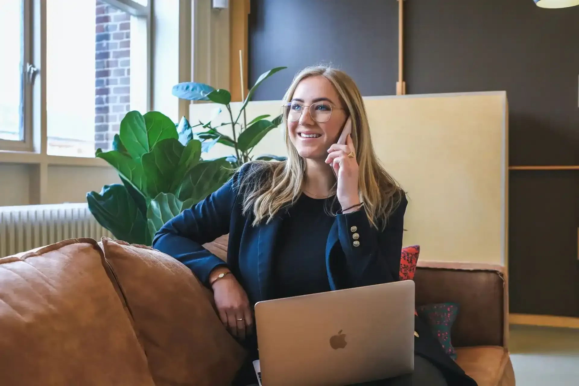 Woman smiling on a sofa with a laptop in a modern living room