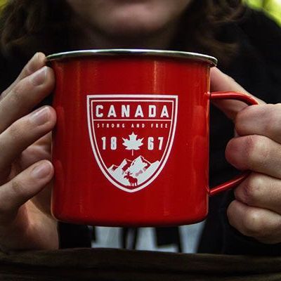 Red Canada mug with white maple leaf emblem held in both hands