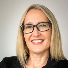 Smiling Frances Wipf with blonde hair and black glasses against a light background