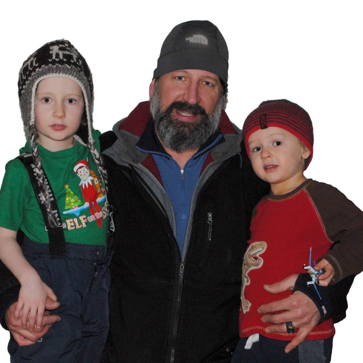 Three people posing together in winter hats and coats, with two children on either side of an adult man.